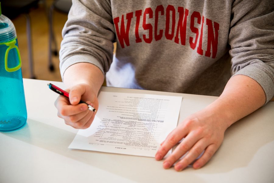 Student wearing WISCONSIN sweater filling out form on table.