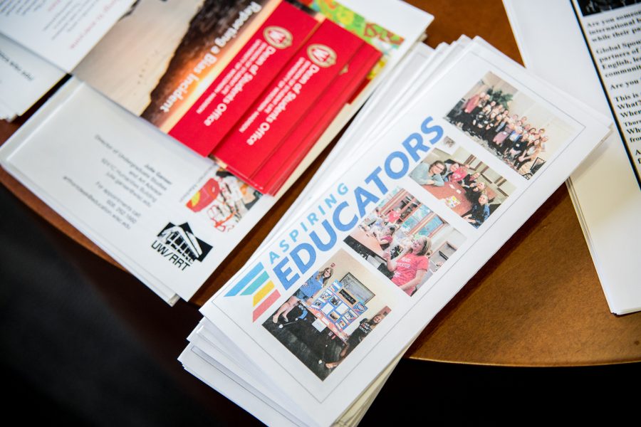 Piles of pamphlets neatly aligned atop of a wooden table; the closest pamphlet says "Aspiring Educators".