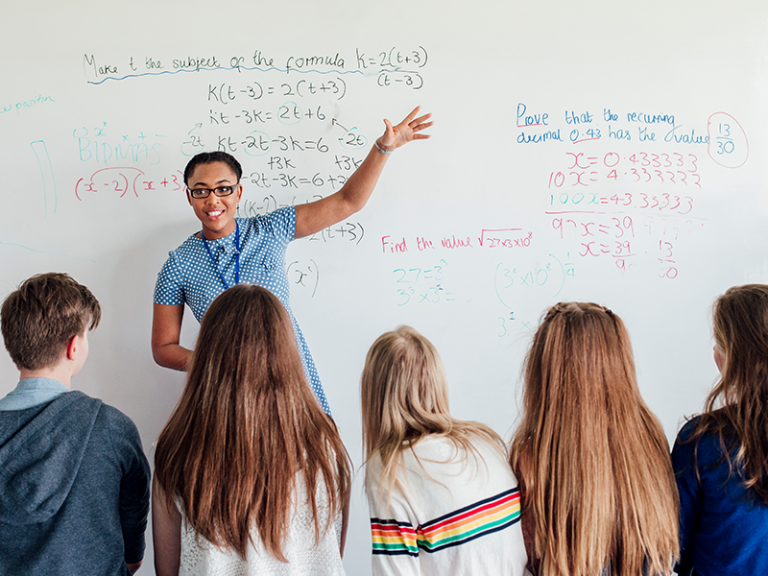 Student teacher showing students how to do a math problem on the white board.