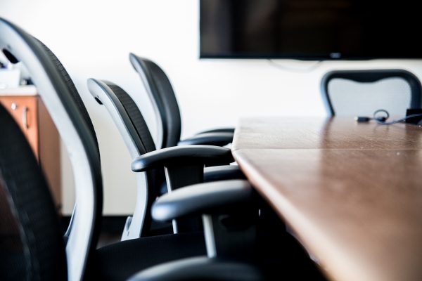 One side of a table with chairs and a television in the background