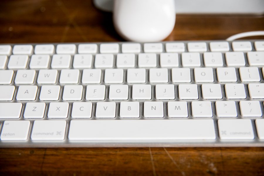 White MAC keyboard on wooden table.