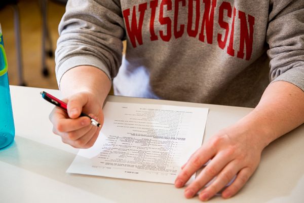Student wearing WISCONSIN sweater filling out form on table.